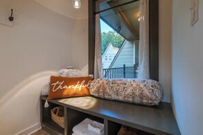 A bathroom with a window, a towel rack, and a shelf with towels and a pillow. - Alpine Evergreen | Upscale A-Frame | Pet Friendly Cabin in Helen, GA (Helen)