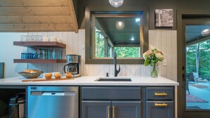 A modern kitchen with a built-in dishwasher, a coffee maker, and a window with a view of the outdoors. - Alpine Evergreen | Upscale A-Frame | Pet Friendly Cabin in Helen, GA (Helen)