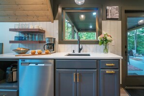 A modern kitchen with a built-in dishwasher, a coffee maker, and a window with a view of the outdoors. - Alpine Evergreen | Upscale A-Frame | Pet Friendly Cabin in Helen, GA (Helen)