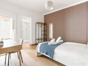 Una camera d'albergo moderna con un letto, una scrivania, una sedia, un armadio e uno specchio.