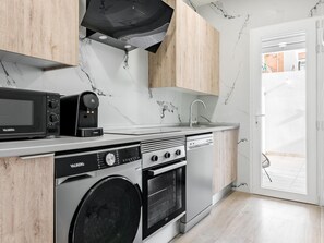 A modern kitchen with a built-in washer, oven, and microwave, a sink, and wooden cabinets.