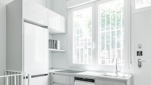 Cucina moderna con mobili bianchi, lavastoviglie, un lavello doppio e una finestra con vista sul verde.