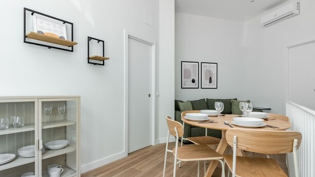 Un'area pranzo moderna con un tavolo rotondo, sedie e una vetrina contenente stoviglie.