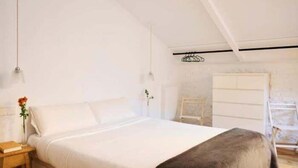 Ein Schlafzimmer mit einem großen Bett, einem Nachttisch mit Lampe und einer Kommode.