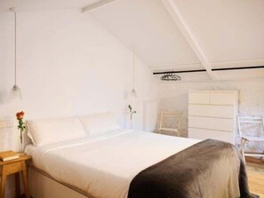 Un dormitorio con una cama grande, una mesita de noche con lámpara y un aparador.