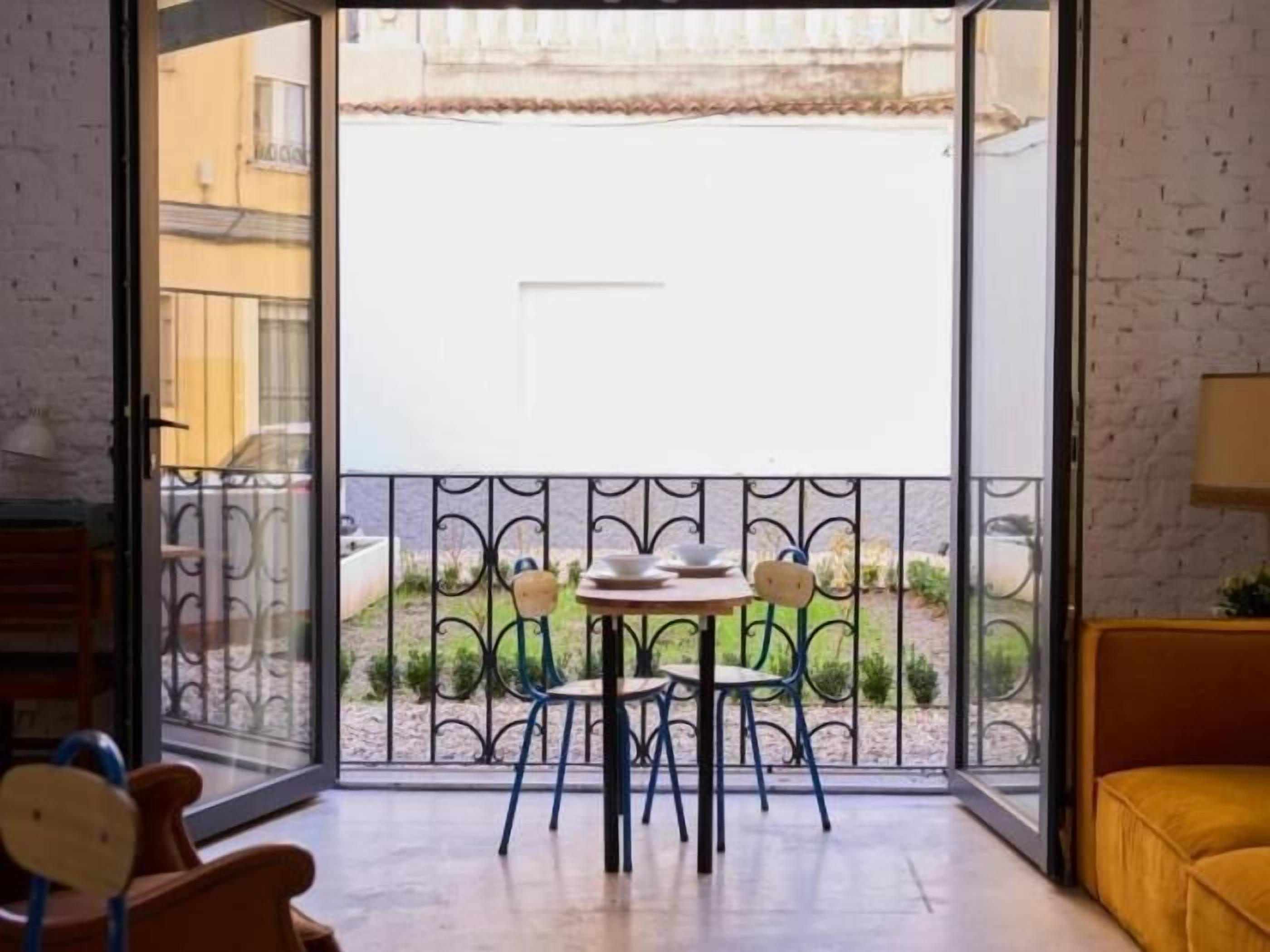 Een kamer met een balkon, een tafel met stoelen en een bank.