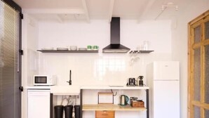 Eine kleine Küche mit Mikrowelle, Kaffeemaschine und einem Kühlschrank.