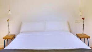 A bed with white bedding, two bedside tables with lamps, and a vase with a flower on each table. - Las Casas de San Félix by Charming 6 - Renovated studio (Ciudad de Madrid)