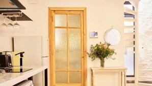 A kitchen with a wooden door, a white countertop, and a small table with a vase. - Las Casas de San Félix by Charming 6 - Renovated studio (Ciudad de Madrid)