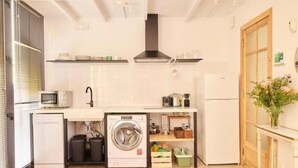 A compact kitchen with a washing machine, microwave, and a small refrigerator. - Las Casas de San Félix by Charming 6 - Renovated studio (Ciudad de Madrid)