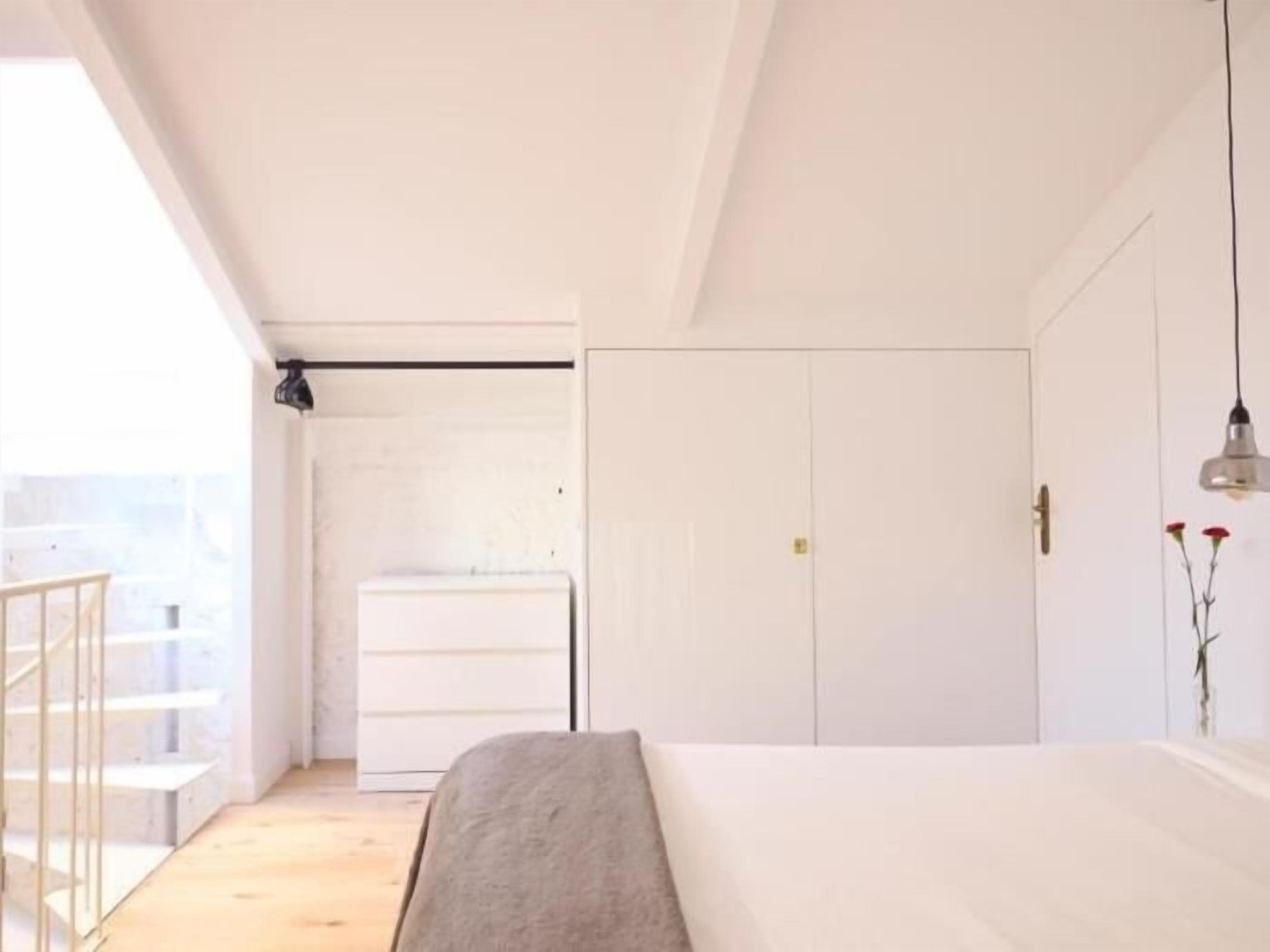 Un dormitorio con cama, armario y vistas a un balcón.