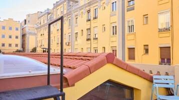 Un edificio amarillo con techo rojo, una ventana pequeña y una silla azul.