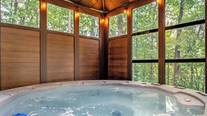 Un jacuzzi con vistas a árboles a través de amplios ventanales.