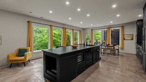 Una cocina moderna con una isla central, ventanas amplias y un comedor con banco.