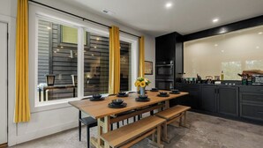 Una cocina moderna con una mesa de madera, bancos y armarios negros.