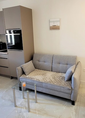 Ein modernes Wohnzimmer mit einem grauen Sofa, einem Einbauofen und einem kleinen Gemälde an der Wand.
