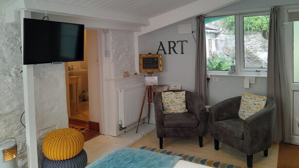 Ein gemütliches Wohnzimmer mit Kamin, zwei Sesseln, einem Fernseher und einem an der Wand befestigten Kunstwerk.
