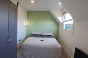 Une chambre à coucher avec un lit, une armoire, une fenêtre et une vue sur la mer.