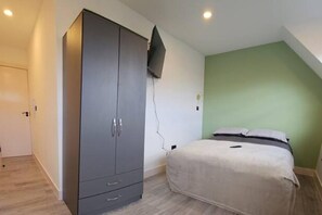 Une chambre à coucher avec un lit, une armoire et un téléviseur fixé au mur.