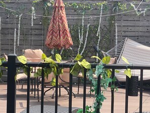 A patio with a hammock, a striped umbrella, and a wooden fence with climbing plants. - Spacious 1BR apartment in welcoming Chicago with Garage Parking (Chicago)