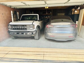 A garage with two vehicles parked inside, a white Bronco and a gray Tesla. - Spacious 1BR apartment in welcoming Chicago with Garage Parking (Chicago)
