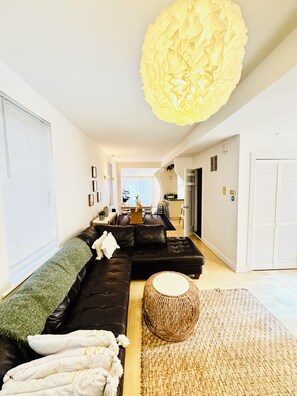 A modern living room with a sofa, a round woven ottoman, and a large decorative light fixture. - Spacious 1BR apartment in welcoming Chicago with Garage Parking (Chicago)