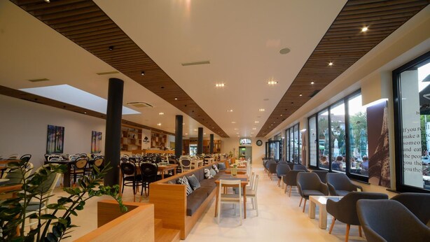 Una cafeteria moderna amb detalls de fusta, zones d'seure i grans finestres.