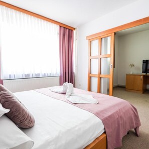 Una habitación de hotel con cama, armario y televisor.