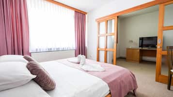 A hotel room with a bed, a desk, a television, and a wardrobe.