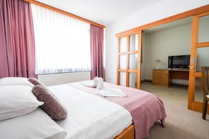 A hotel room with a bed, a desk, a television, and a wardrobe.