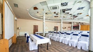 Una sala de conferències amb una taula llarga, files de cadirees i un sostre alt amb un dibuix de reixa.