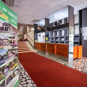 A hotel lobby with a reception desk, a staircase, and a red carpet leading to the upper floor. - Park (Bihac)