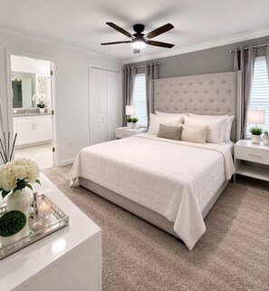 A bedroom with a large bed, a ceiling fan, a nightstand with a lamp, and a dresser with a tray of decorative items. - Spacious 4-bedroom house with AC in pleasant Kissimmee (Kissimmee)