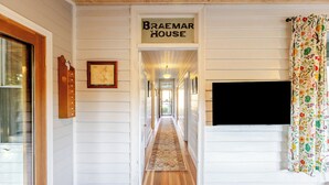 A hallway with a sign reading 'Braemar House,' a framed picture, a television on the wall, and a patterned curtain.
