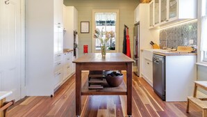 A kitchen with a central island, wooden flooring, white cabinetry, and a window with a view.