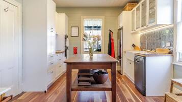 A kitchen with a central island, wooden flooring, white cabinetry, and a window with a view.
