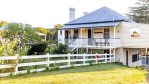 A two-story house with a balcony, a fenced yard, and a garden.