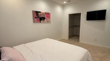 Une chambre à coucher avec un lit, un tableau, une télévision et un placard.