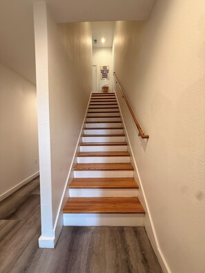 A staircase with wooden steps and a handrail, leading to a landing with a sign.