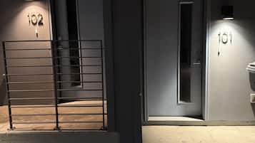 A building entrance with two doors labeled '102' and '101', a metal gate, and a concrete floor.