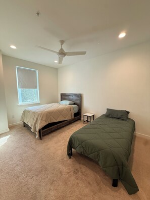 Une chambre avec deux lits, un ventilateur de plafond et une fenêtre.