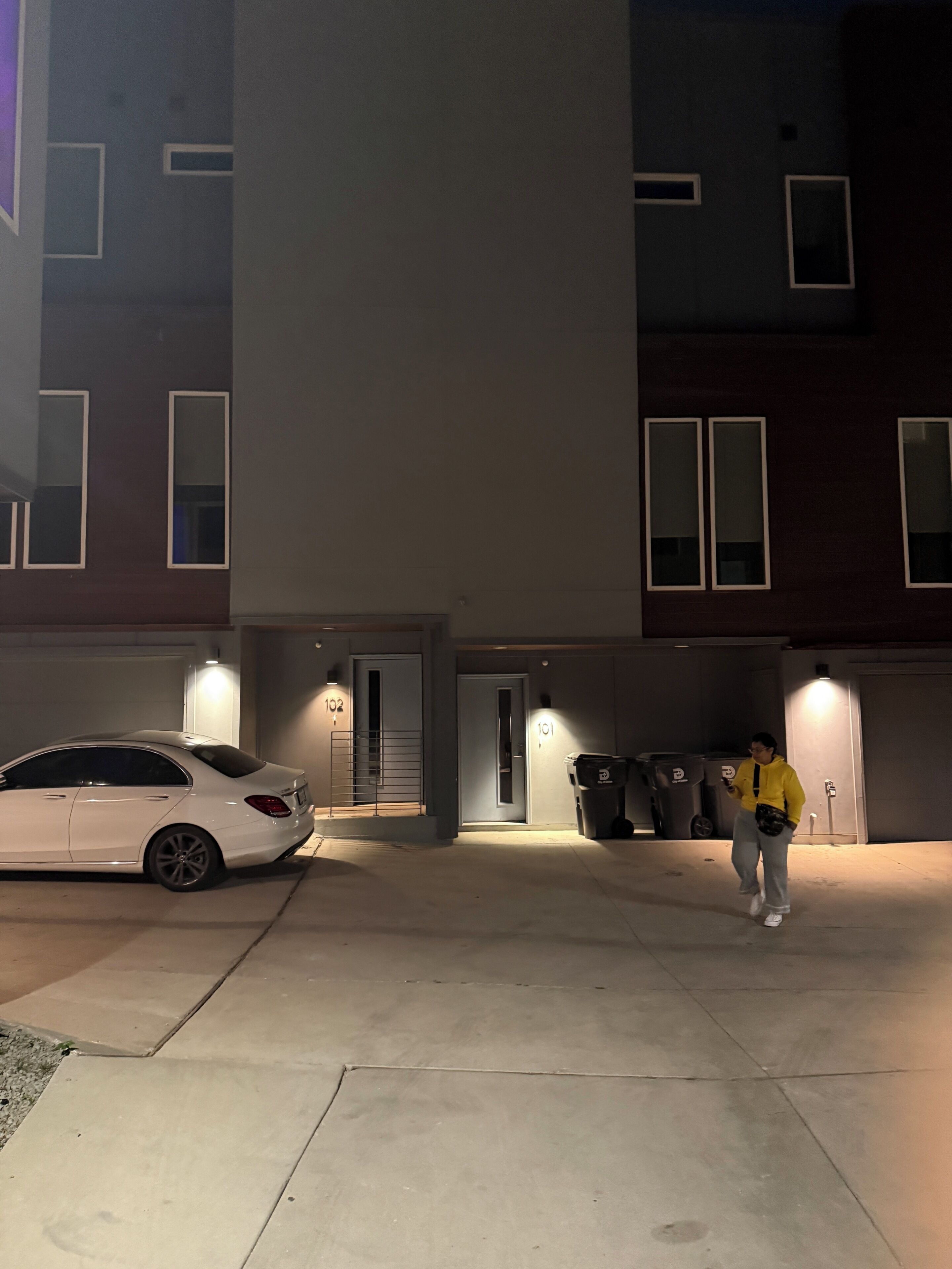 Eine Parkgarage mit einem weißen Auto vor einem Gebäude mit nummerierten Türen.