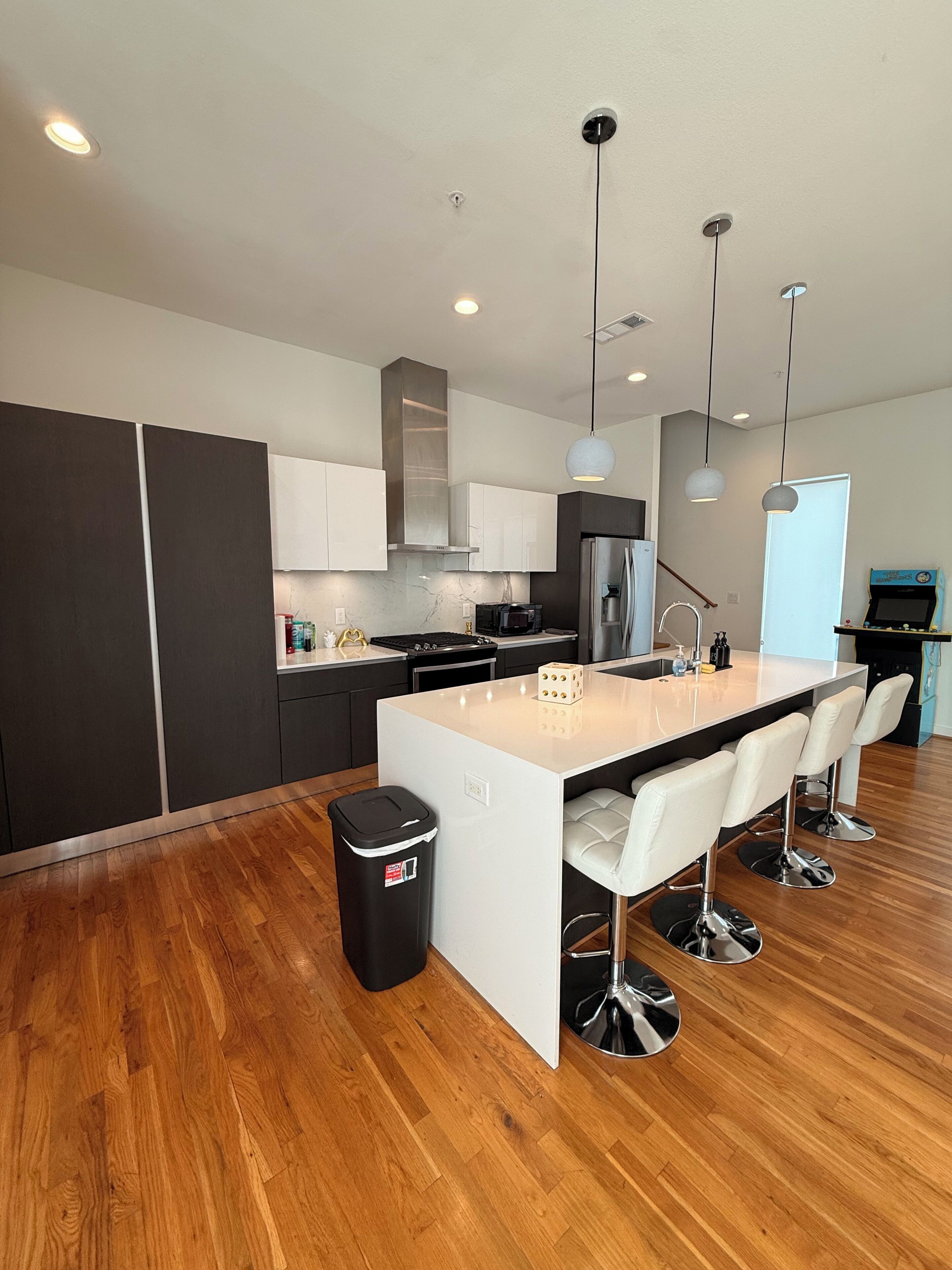 A modern kitchen with a central island, stainless steel appliances, and pendant lighting.