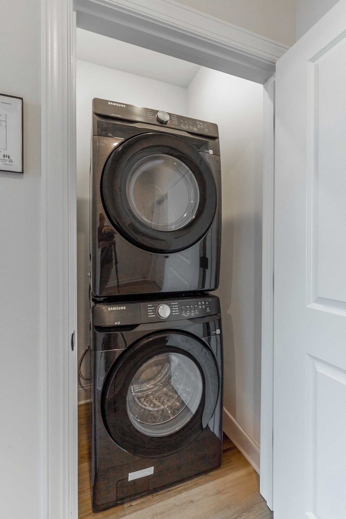 Une machine à laver et un sèche-linge superposés, installés dans un couloir.