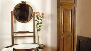 A room with a wooden chair, a round mirror, a small table, and a vase with flowers. - Hotel Restaurante Casa Del Maco (Benissa)