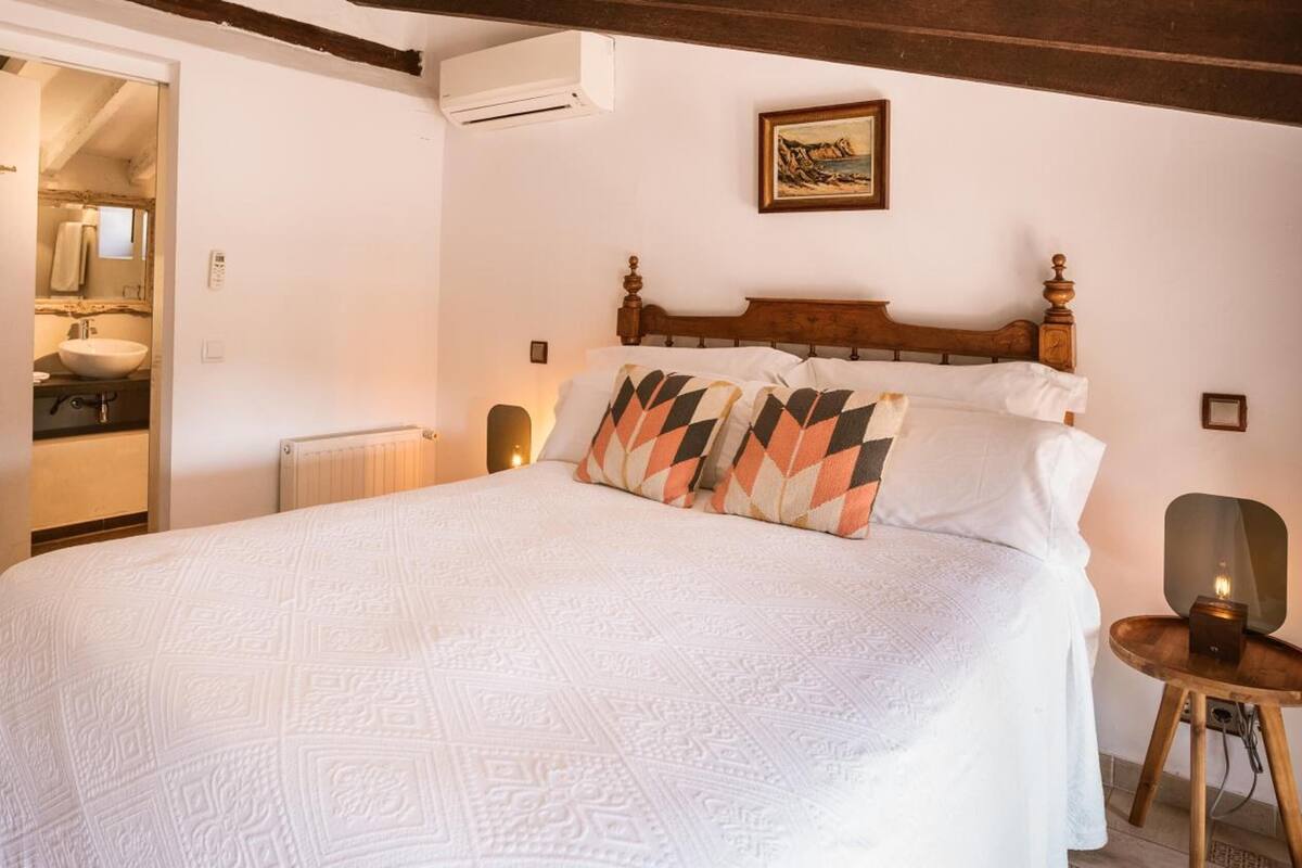 Ein Schlafzimmer mit Bett, Nachttisch, Heizkörper, Klimaanlage und einem Bild an der Wand.