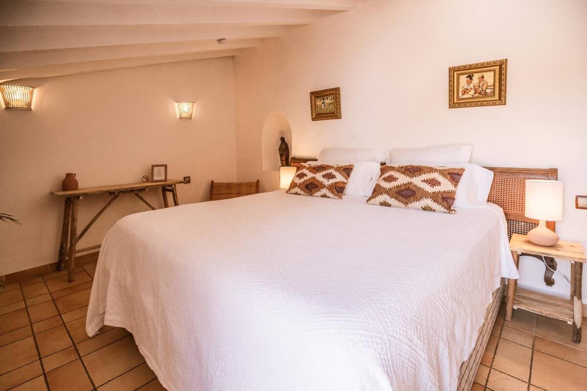 Ein ordentlich eingerichtetes Schlafzimmer mit einem großen Bett, Nachttischlampen und Wandbildern.