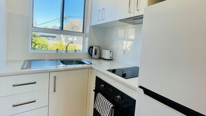 Una cocina moderna con ventana, electrodomésticos de acero inoxidable y armarios blancos.