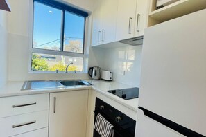A modern kitchen with a window, stainless steel appliances, and white cabinetry.