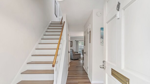 A staircase leading to a landing with a door on the right. - Beautiful Coastal Townhome | 2BR/1.5BA | Private Patio | Minutes to Pier Village & Beaches (Saint Simons Island)